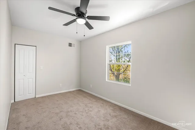 an empty room with windows and fan