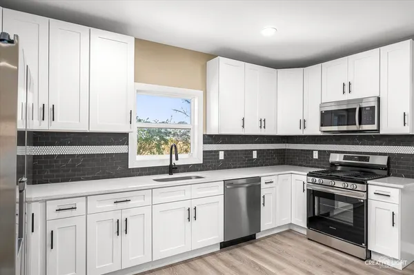 a kitchen with granite countertop white cabinets white stainless steel appliances and a sink