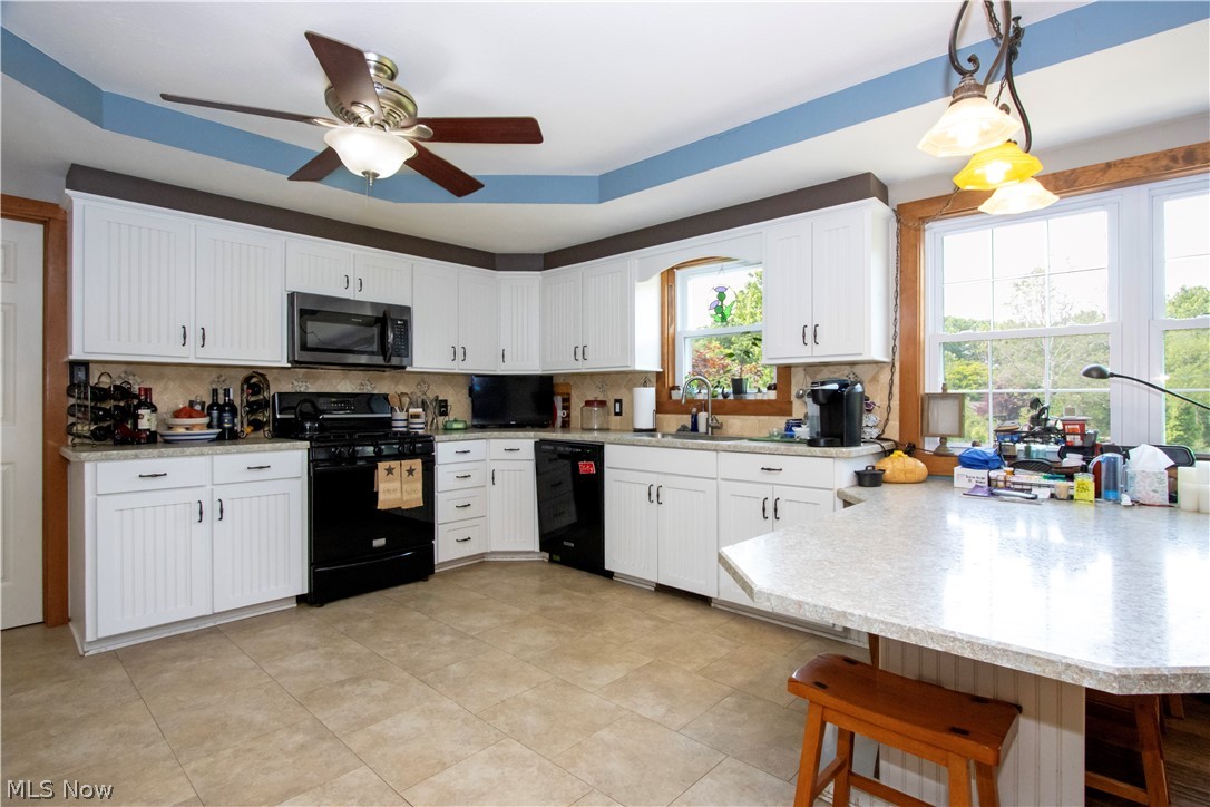 1043 North Honeytown Road Wooster, OH 44691 - Photo 6 of 46 Kitchen featuring white cabinetry with beadboard paneling, light-toned countertops, tile flooring, and a ceiling fan with integrated lighting