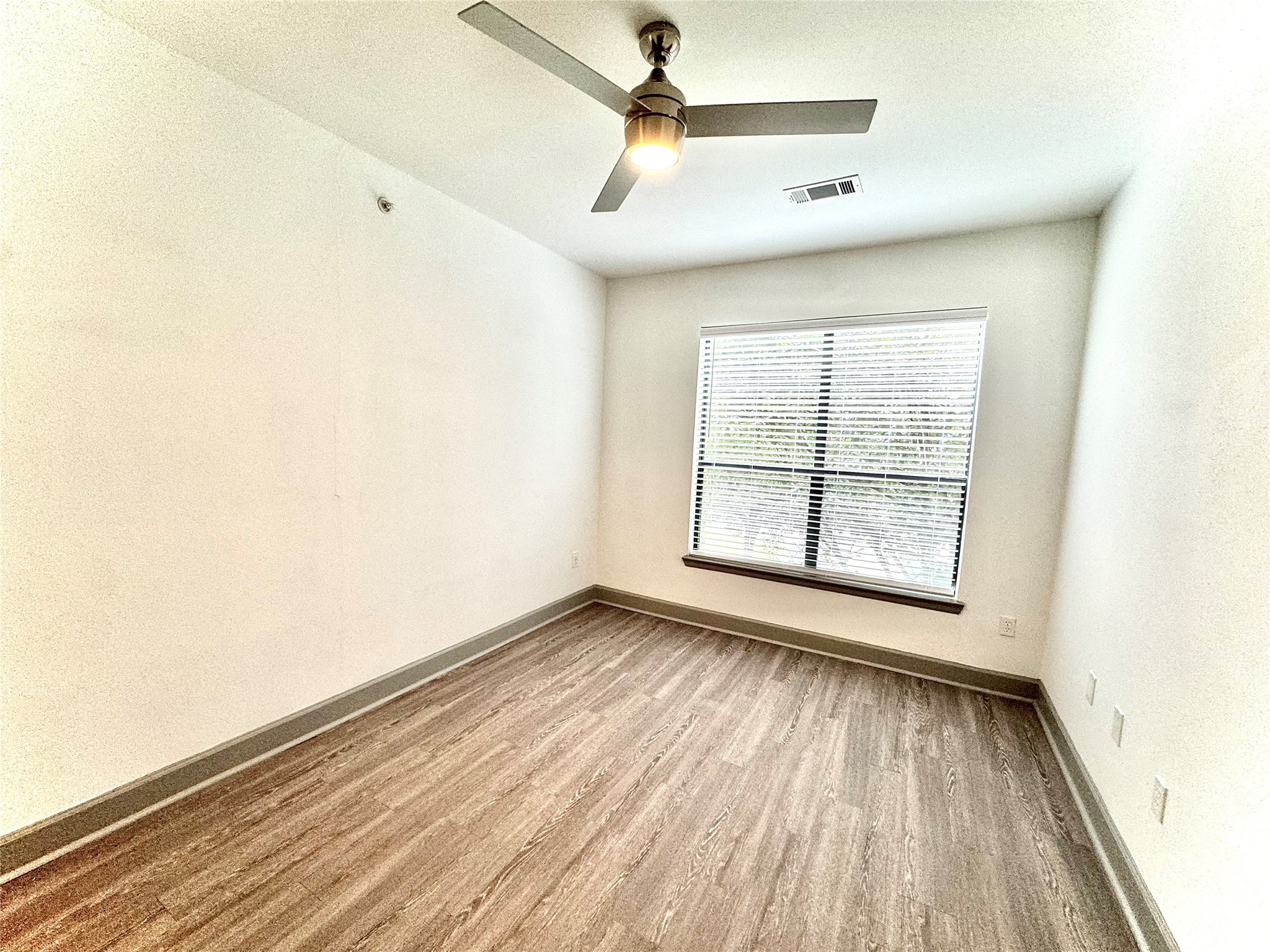 3333 Weslayan Street, Unit 1412 Houston, TX 77027 - Photo 9 of 20 an empty room with wooden floor fan and windows
