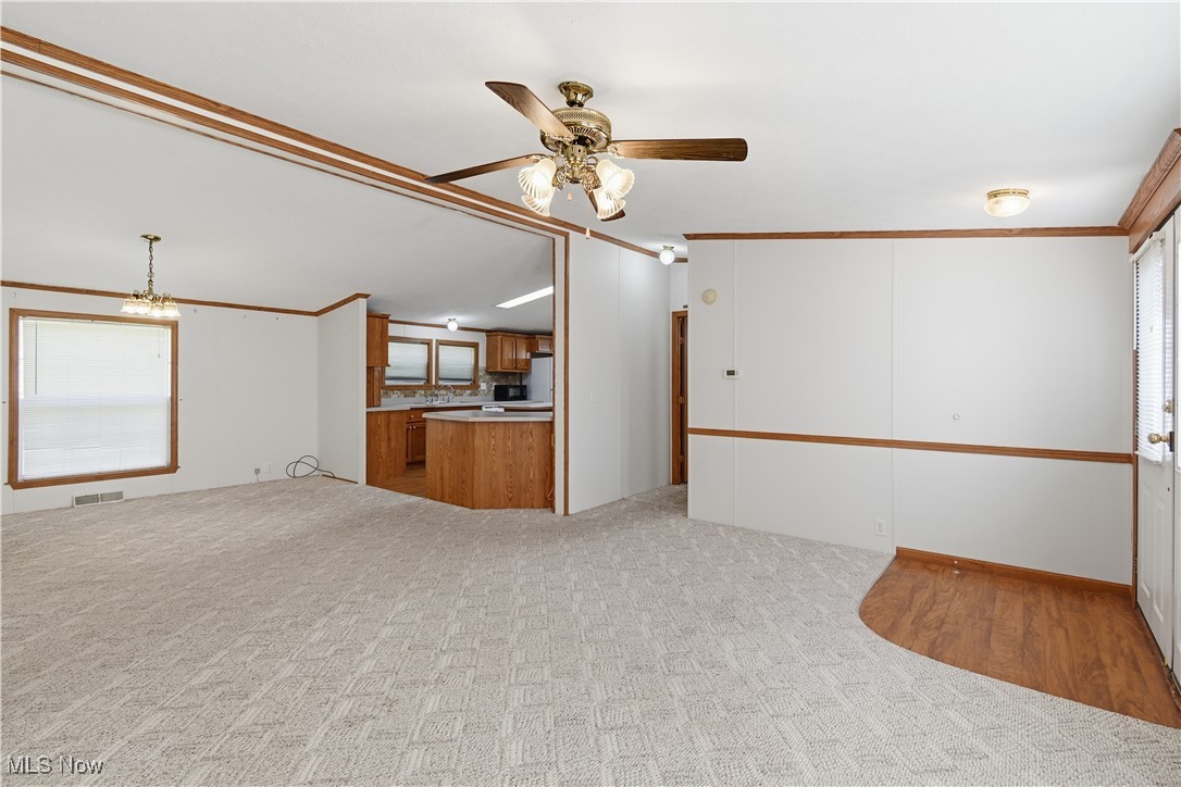 60602 Shaw Road Cambridge, OH 43725 - Photo 9 of 41 Unfurnished living room featuring healthy amount of natural light, crown molding, light carpet, a ceiling fan, and vaulted ceiling