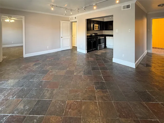 a view of an empty room with kitchen and window