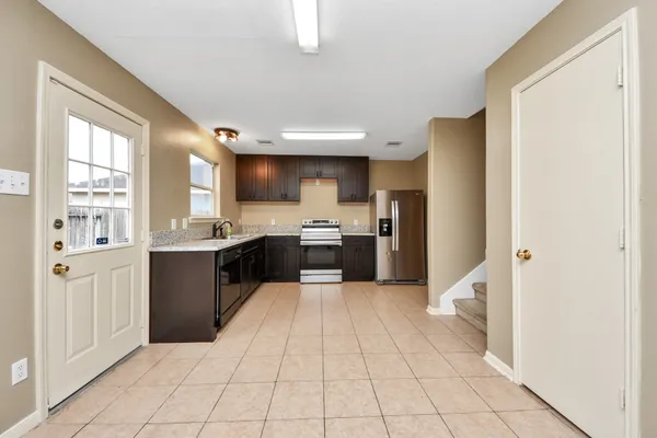 a large kitchen with a large counter top a sink a refrigerator and cabinets