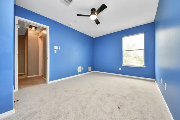 an empty room with windows and ceiling fan