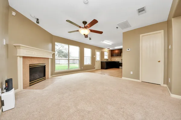 a view of an empty room with a fireplace and a ceiling fan