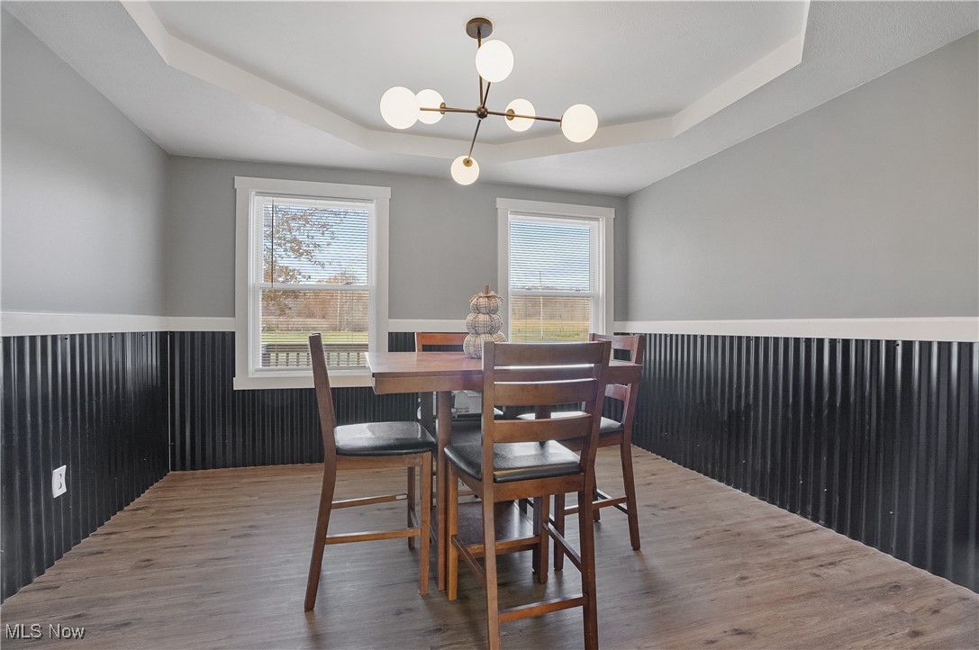 9278 Bryant Road Windham, OH 44288 - Photo 18 of 47 Dining space with a raised ceiling, wood finished floors, a chandelier, and wainscoting