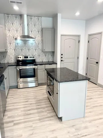 a kitchen with stainless steel appliances granite countertop a stove a sink and a microwave