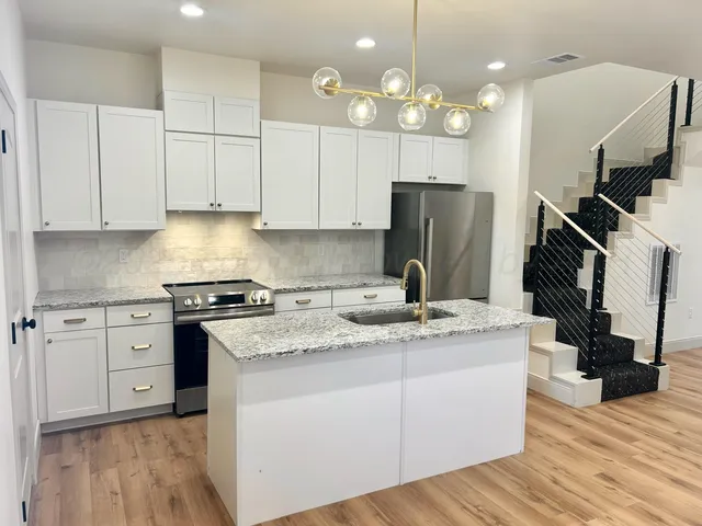 a kitchen with kitchen island granite countertop a sink cabinets and stainless steel appliances