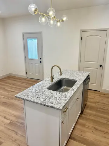 a kitchen with stainless steel appliances granite countertop a sink dishwasher and cabinets with wooden floor