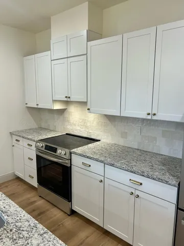 a kitchen with granite countertop white cabinets and a stove