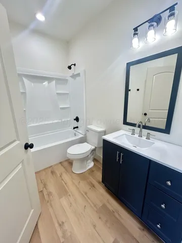 a bathroom with a bathtub shower sink vanity mirror and toilet