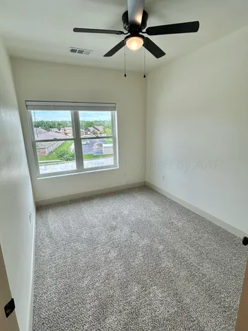 an empty room with windows and fan