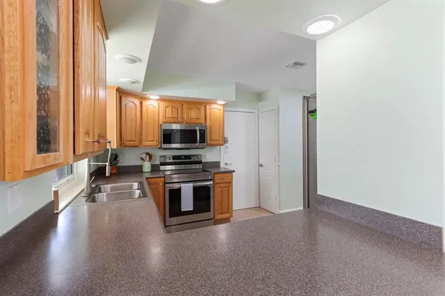 a kitchen with stainless steel appliances a stove a sink and white cabinets
