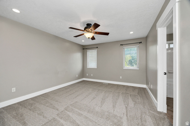 2912 South 1080th Street West Logan, UT 84321 - Photo 10 of 43 Spacious room featuring neutral carpeting, light gray walls, a ceiling fan with integrated lighting, recessed lighting, and two windows with blinds