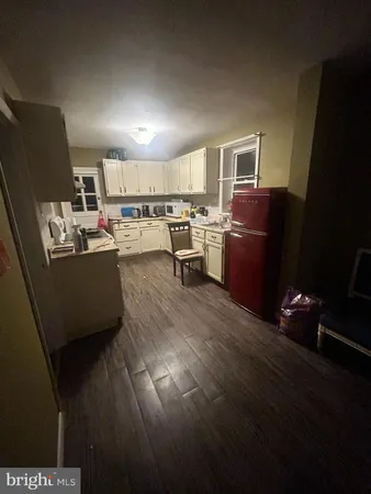 a living room with couches and kitchen view with wooden floor