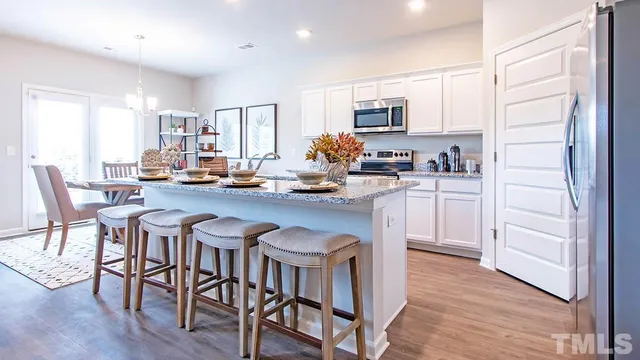 a kitchen with stainless steel appliances granite countertop a table chairs microwave and sink