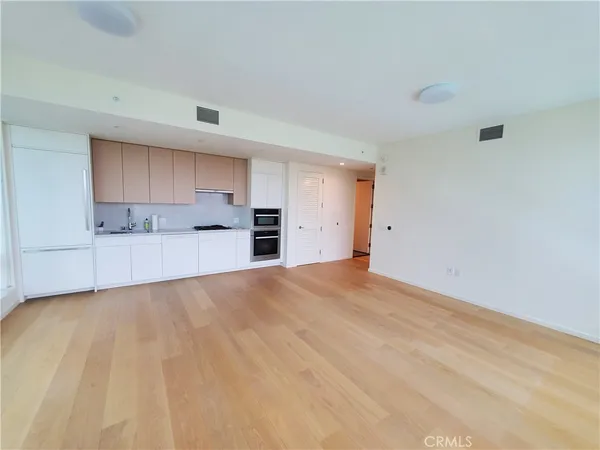 a view of empty room with a kitchen and refrigerator