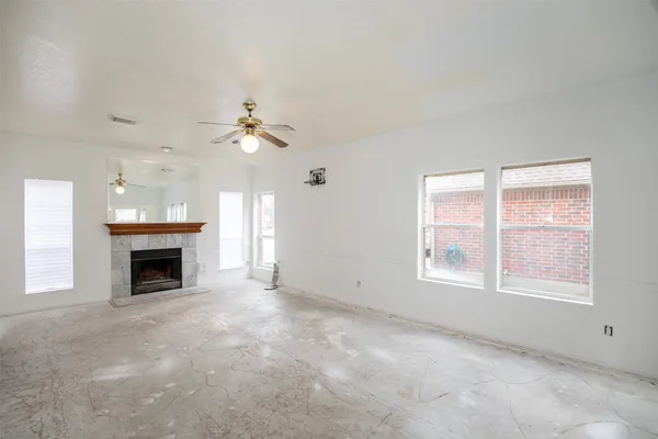 an empty room with windows and fireplace
