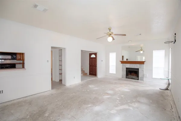 an empty room with fireplace fan and windows
