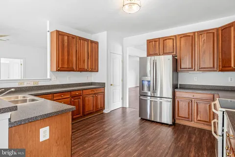 an empty room with wooden floor a ceiling fan and windows