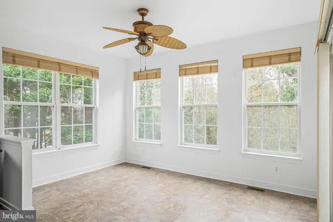 an empty room with wooden floor windows and fan
