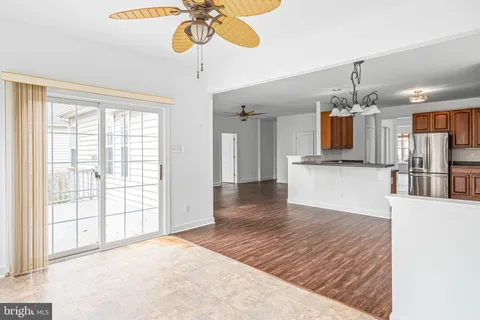 a view of an empty room with wooden floor and a ceiling fan