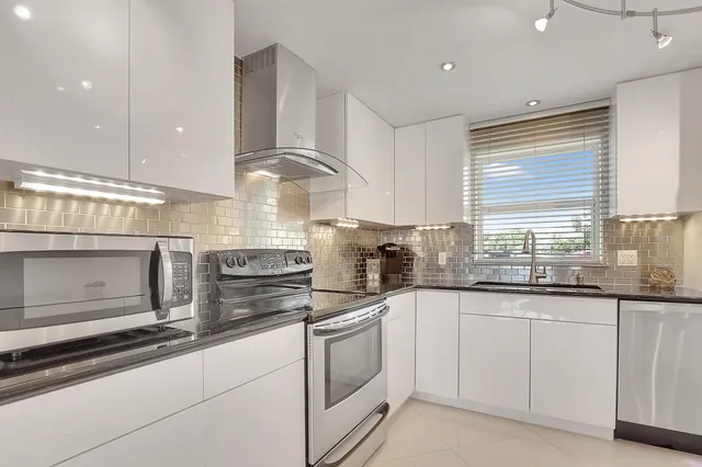 a kitchen with granite countertop white cabinets white appliances and a sink