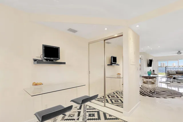 a living room with furniture a flat screen tv and a refrigerator