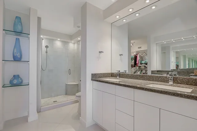 a bathroom with a granite countertop sink a toilet a shower and a mirror