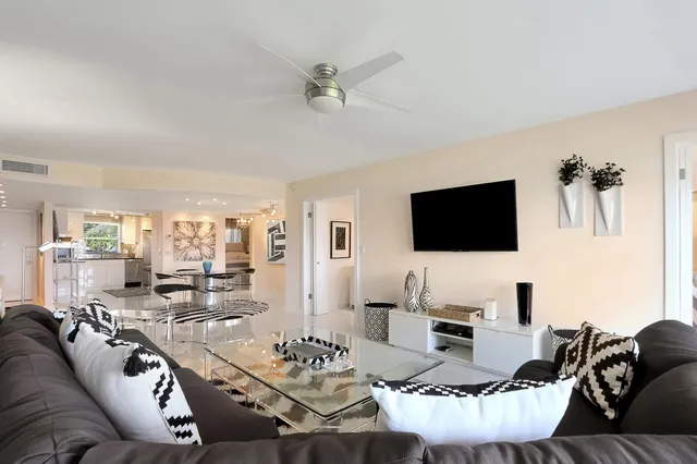a living room with furniture kitchen view and a flat screen tv