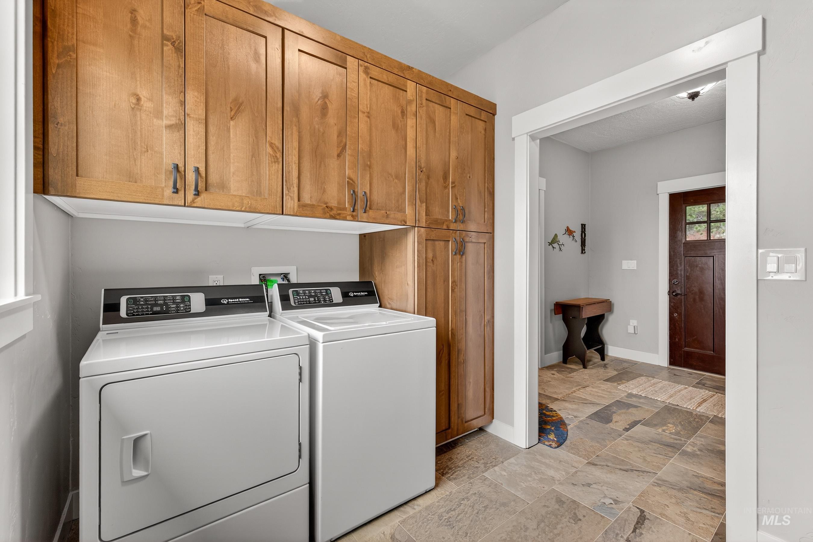 10191 Timberrim Drive Cascade, ID 83611 - Photo 12 of 44 Laundry area featuring washer and clothes dryer, light stone finish floors, and cabinet space