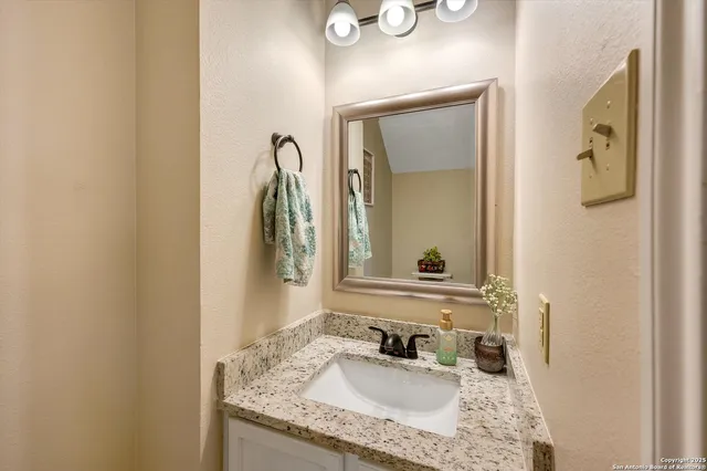 a bathroom with a granite countertop sink and a mirror