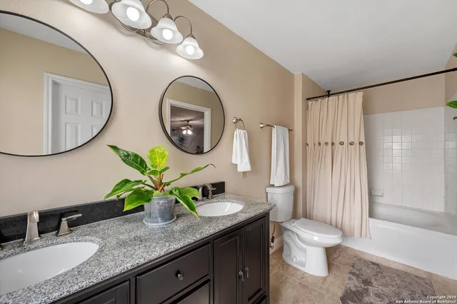 a bathroom with a granite countertop toilet sink and mirror