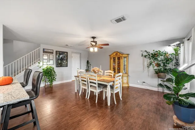 a dining room with furniture potted plants and wooden floor