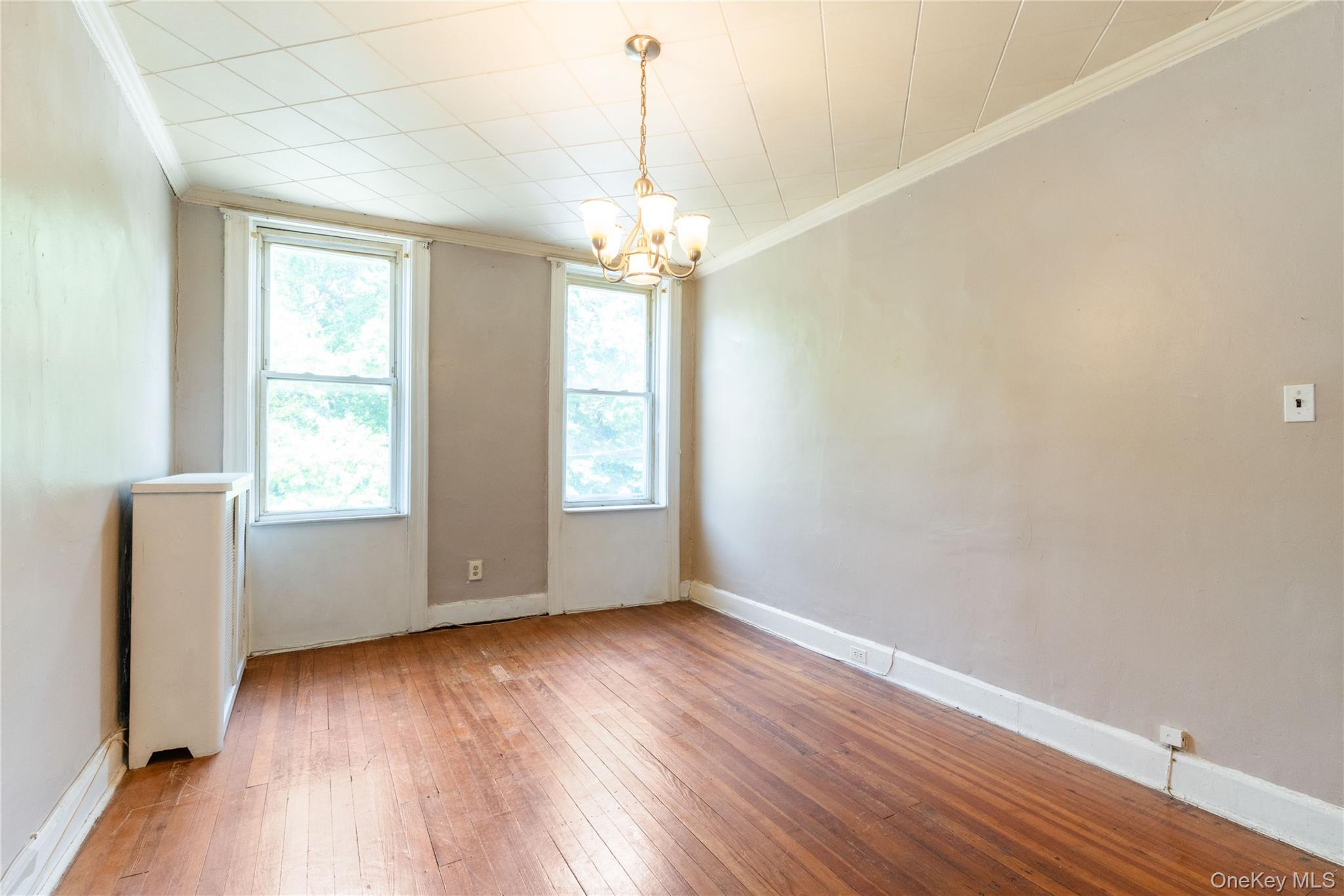 82-72 88th Place Queens, NY 11421 - Photo 9 of 26 an empty room with wooden floor and windows