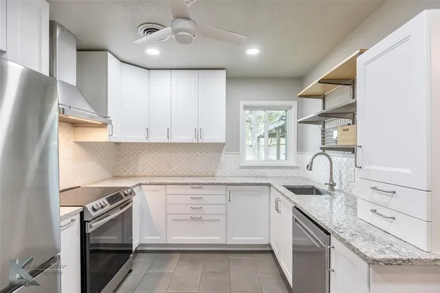 a kitchen with stainless steel appliances granite countertop a refrigerator a sink and white cabinets