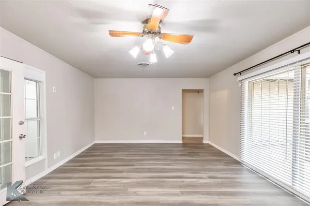a view of an empty room with wooden floor and a window