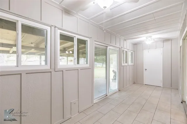 a view of an empty room with wooden floor and a ceiling fan