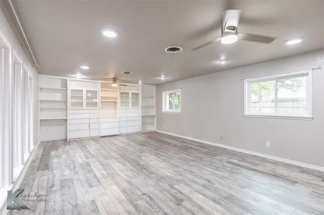 a view of a hallway with wooden floor and a bathroom