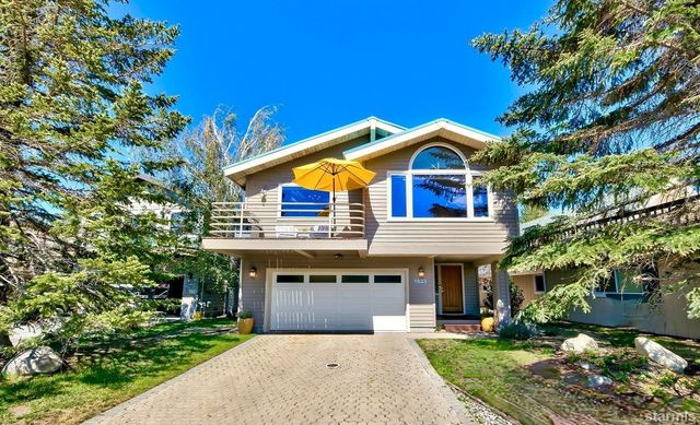 a front view of a house with a garden and trees