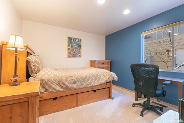 a bedroom with a bed a desk and chair with window