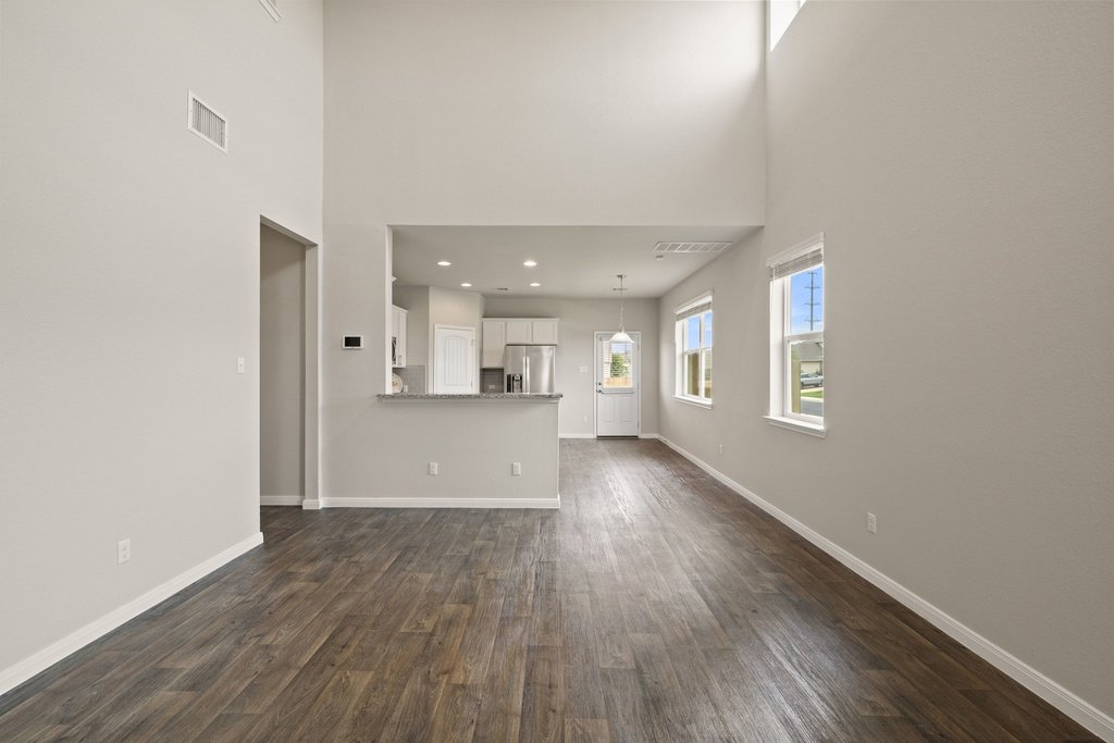 102 Ashford Way Georgetown, TX 78626 - Photo 6 of 28 Lofty ceilings and rich hardwood-style flooring distinguish this open-concept great room, flowing seamlessly into the kitchen.