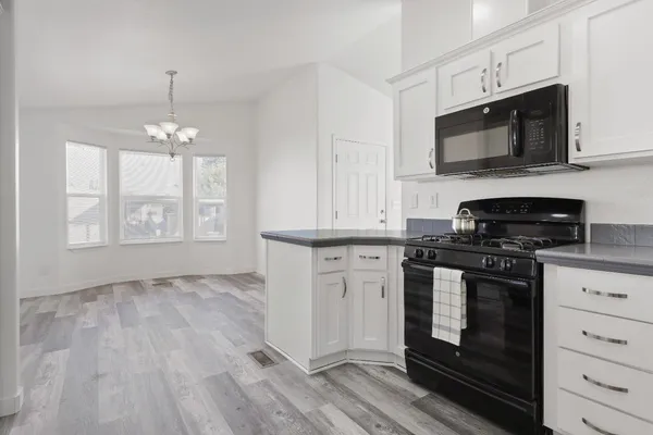 a kitchen with stainless steel appliances granite countertop a stove a microwave and a white cabinets