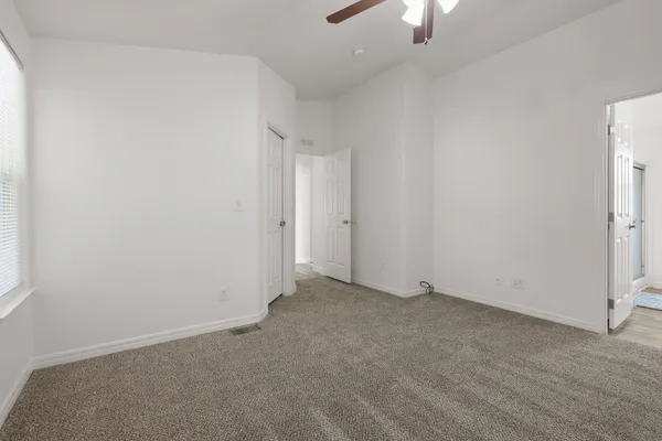 an empty room with ceiling fan window and closet