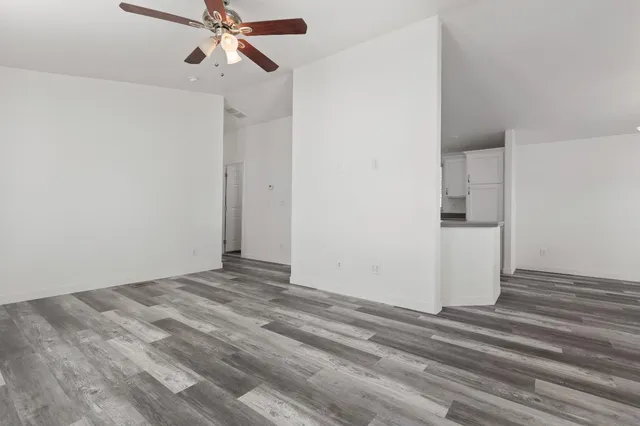a view of room with a ceiling fan and wooden floor