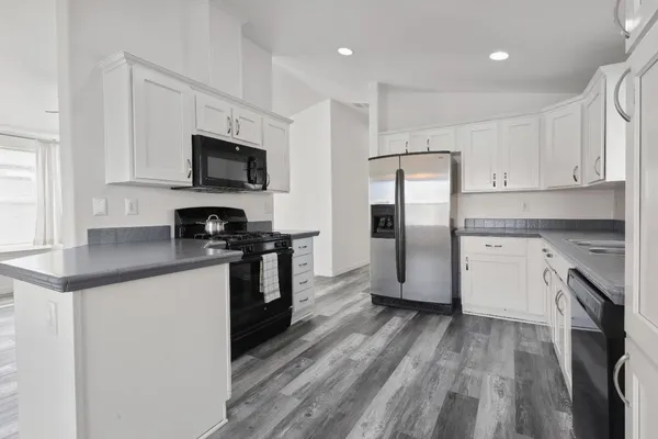 a kitchen with stainless steel appliances granite countertop a refrigerator a stove top oven a sink and dishwasher