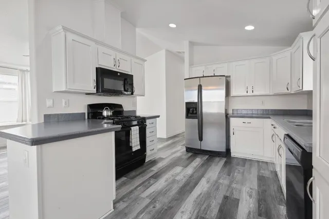 a kitchen with stainless steel appliances granite countertop a refrigerator a stove top oven a sink and dishwasher