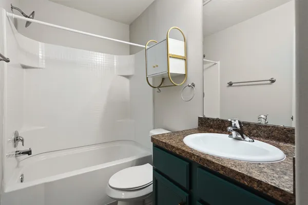 a bathroom with a granite countertop sink a toilet and shower