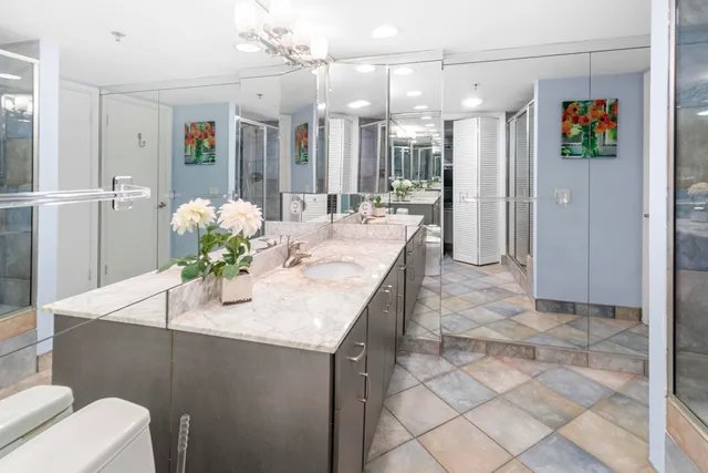 a bathroom with a granite countertop sink a toilet a mirror and shower