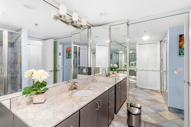 a bathroom with a granite countertop sink a toilet a mirror and shower
